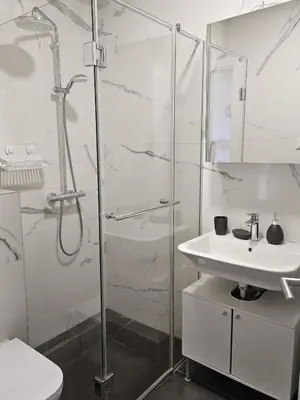 a white bathroom with a shower and a sink at Apartament Onyx in Becici