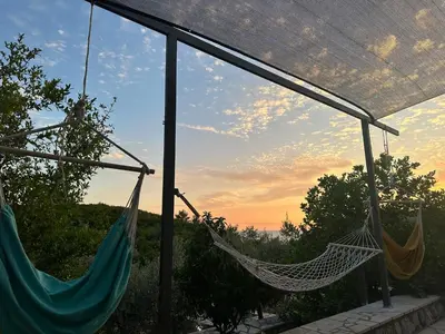 two hammocks on a porch with the sunset in the background at Golden Ray Bigova in Bigovo