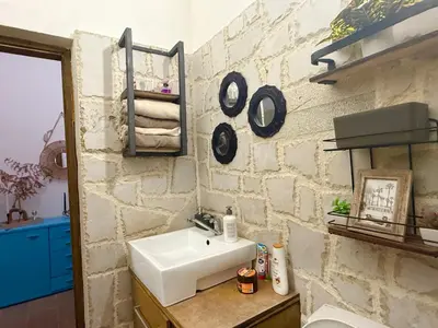 a bathroom with a sink and a stone wall at Golden Ray Bigova in Bigovo