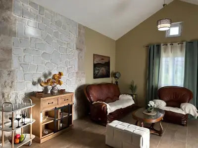 a living room with leather chairs and a stone wall at Golden Ray Bigova in Bigovo