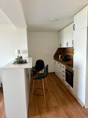 a kitchen with white cabinets and a counter and two chairs at Harmonia in Dobra Voda