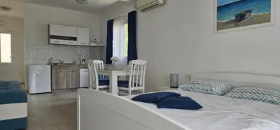 a bedroom with a large bed and a kitchen at Aqua Apartments in Bigovo