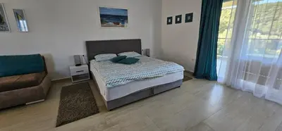 a bedroom with a bed with blue pillows and a couch at Aqua Apartments in Bigovo