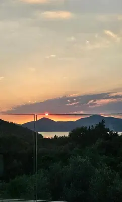 a sunset over the mountains with the sun setting in the distance at Aqua Apartments in Bigovo