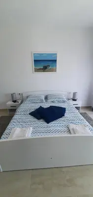 a white bed with blue pillows in a bedroom at Aqua Apartments in Bigovo