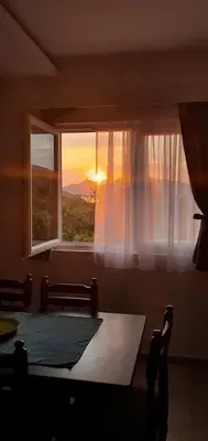 a room with a table and a window with the sunset at Aqua Apartments in Bigovo