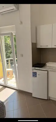 a kitchen with a white refrigerator and a sliding glass door at Apartmani Sutomore in Sutomore