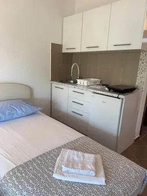 a room with a bed with a sink and a kitchen at Apartmani Sutomore in Sutomore