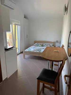 a bedroom with a bed and a table and a table and chair at Apartmani Sutomore in Sutomore