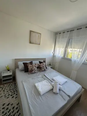 a bedroom with a large bed with white sheets and pillows at Zagi Apartment in Ulcinj