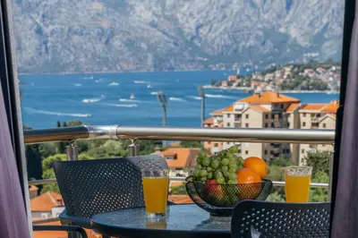 a table with a bowl of fruit and two glasses of beer at Monte Bay Apartments in Kotor