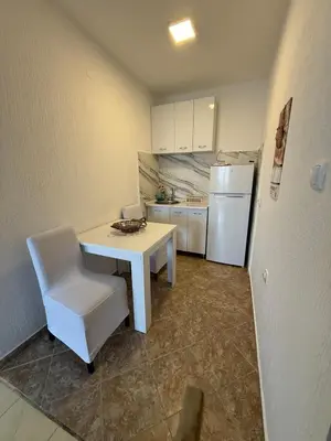 a kitchen with a white table and a white refrigerator at Mila apartman in Budva