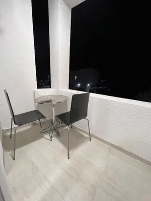 a table and two chairs on a balcony at night at Apartmani Amira Sutomore in Sutomore