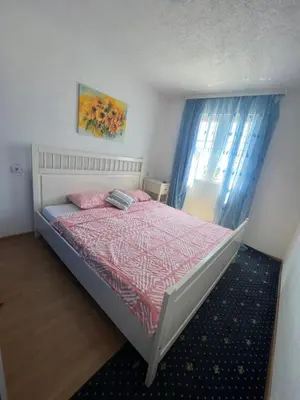 a bedroom with a bed and a window with blue curtains at Apartmani Amira Sutomore in Sutomore