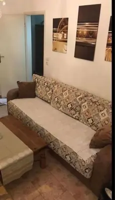 a couch sitting in a living room with paintings on the wall at Apartmani Amira Sutomore in Sutomore