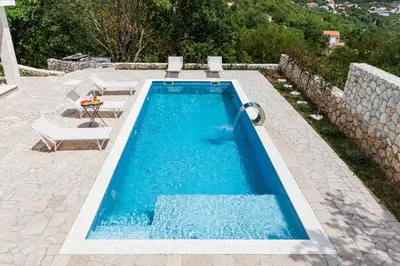 a swimming pool with two chairs and a table at Villa 53 in Lapčići