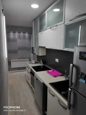 a kitchen with white cabinets and a refrigerator at Apart102 in Budva