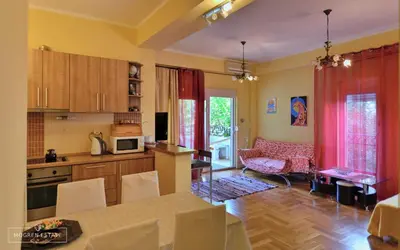 a kitchen and living room with red curtains and a table at Квартира - Солнце in Budva