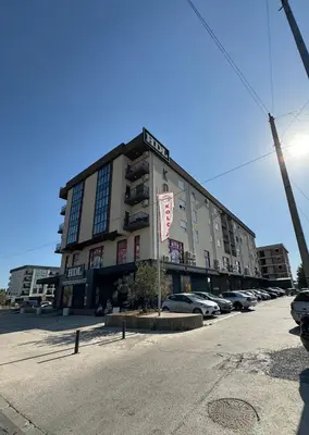 a large building with cars parked in a parking lot at Aron Apartment in Tuzi