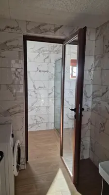 a bathroom with a glass door and a stone wall at Sunset Villa in Bar