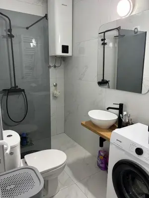 a bathroom with a toilet and a sink and a washing machine at Apartman Sonib in Ulcinj