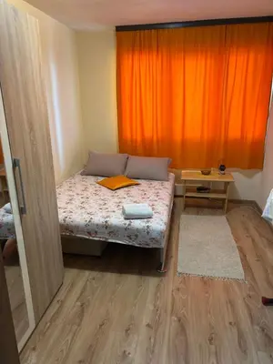 a small room with a bed with an orange curtain at Apartman Sonib in Ulcinj