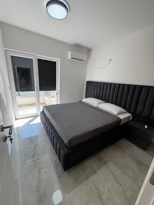 a bedroom with a large bed and two windows at Mona in Ulcinj