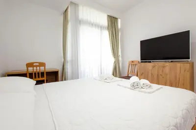 a bedroom with a white bed with a flat screen tv at Hotel PIO in Ulcinj
