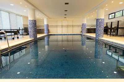 a swimming pool with blue tile columns in a building at Hotel PIO in Ulcinj