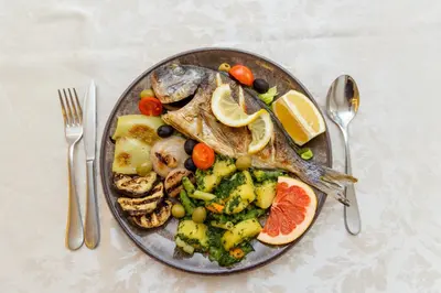a plate of food with a fish and vegetables at Hotel PIO in Ulcinj