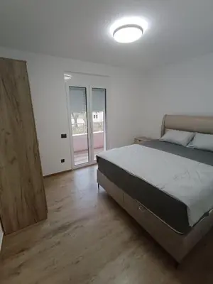 a bedroom with a large bed and a wooden floor at ApartmentsMD apartman 6 najlepse sto zivot pruza in Sutomore