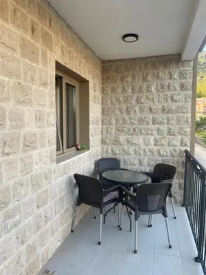 a patio with a table and chairs on a stone wall at Apartman Anastasija in Kotor
