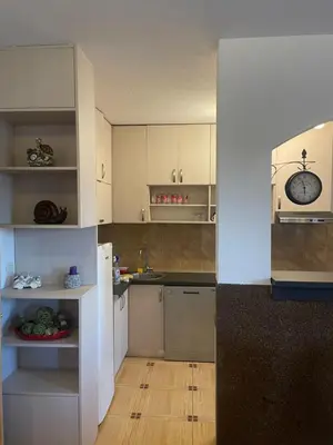 a kitchen with white cabinets and a wooden floor at Apartman Anastasija in Kotor