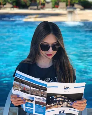 a woman reading a magazine in front of a pool at Perla Luxury in Ulcinj