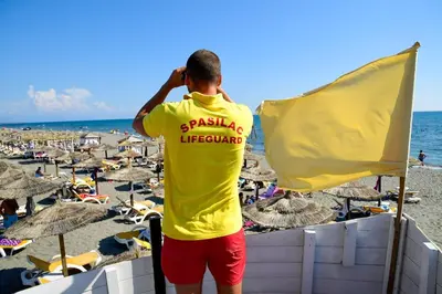 a man talking on a cell phone at the beach at Perla Luxury in Ulcinj