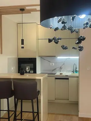 a kitchen with white cabinets and a table with chairs at Alex 2210 in Podgorica