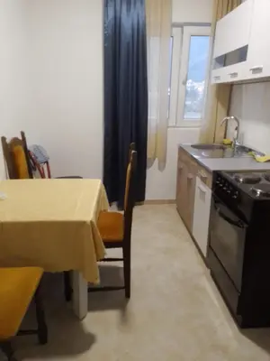 a kitchen with a table and a sink and a table and chairs at Nada Apartman in Lastva