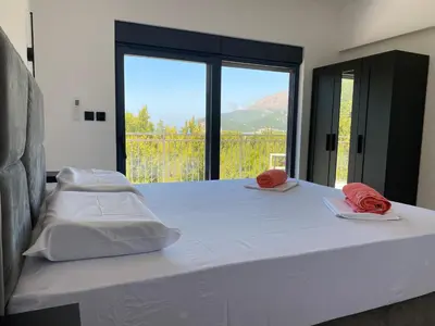 a bedroom with a large white bed with a large window at Maginja in Petrovac na Moru