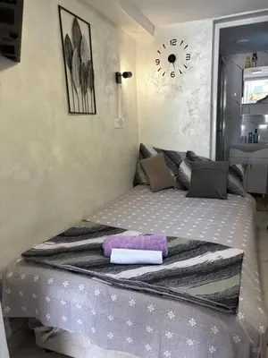 a bed in a room with a clock on the wall at Nina apartman in Budva