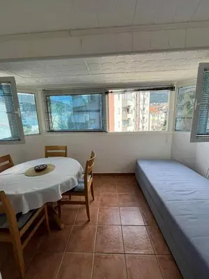 a room with a table and a bed and windows at Marko's place in Budva