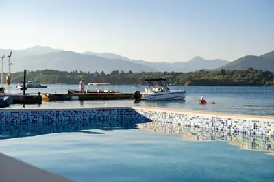a swimming pool with a boat in a body of water at Vila PETICA in Tivat