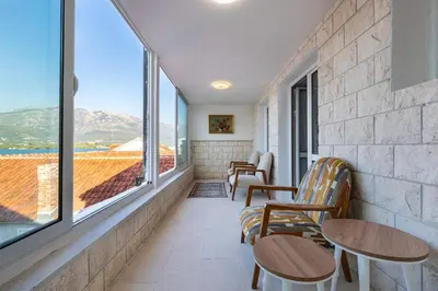 a room with two chairs and tables and windows at Vila PETICA in Tivat