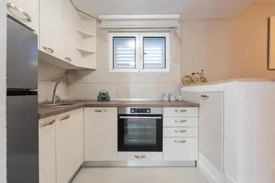 a kitchen with white cabinets and a window at Vila PETICA in Tivat