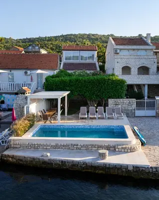 a house with a swimming pool in the water at Vila PETICA in Tivat