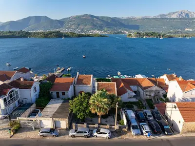 a town with cars parked in a parking lot next to the water at Vila PETICA in Tivat