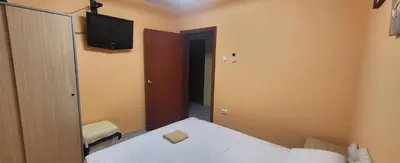 a small room with a bed and a tv on the wall at UGS Apartment in Sutomore