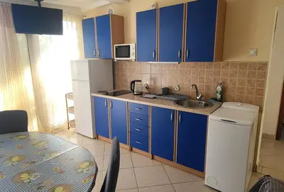 a kitchen with blue cabinets and a sink and a table at UGS Apartment in Sutomore