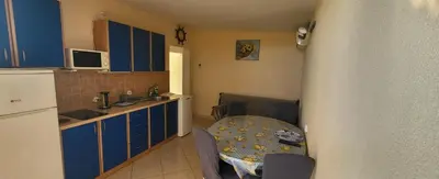 a kitchen with blue cabinets and a sink and a table at UGS Apartment in Sutomore