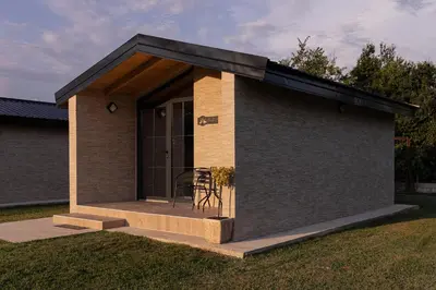 a small house with a porch with a black roof at Rural stay Miranovic in Balabani