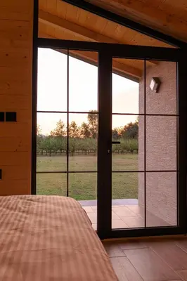 a bedroom with a large glass door with a view of a field at Rural stay Miranovic in Balabani